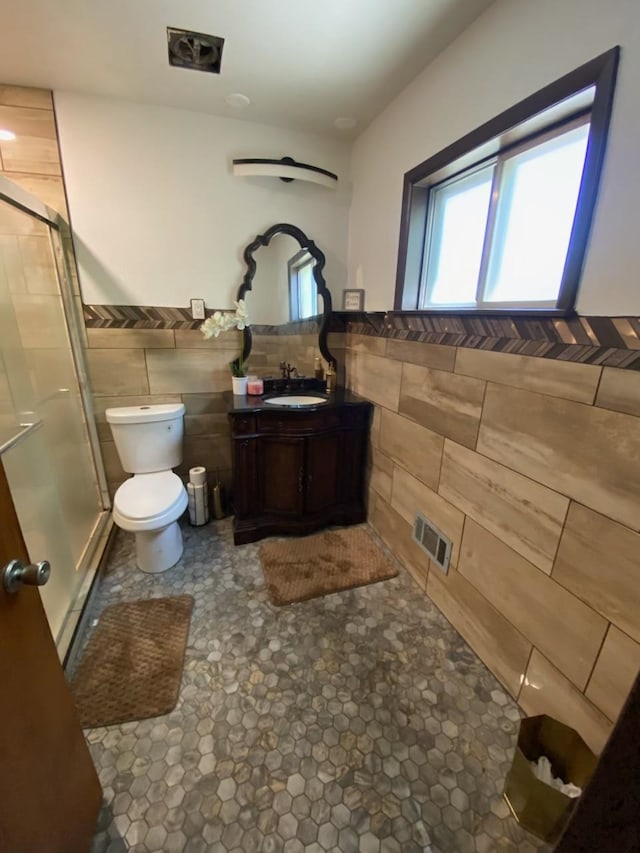 bathroom featuring tile walls, walk in shower, vanity, and toilet