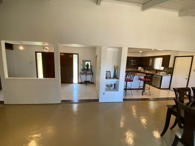 unfurnished living room featuring beam ceiling and high vaulted ceiling