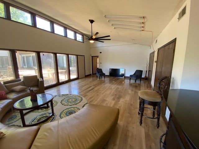 living room with ceiling fan, wood-type flooring, high vaulted ceiling, and a healthy amount of sunlight