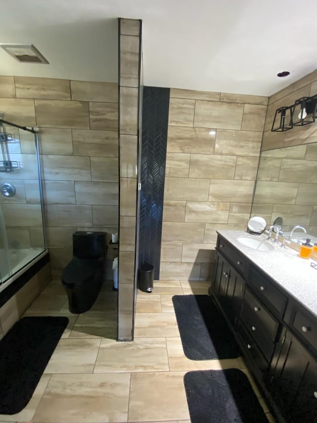 bathroom featuring tile walls, vanity, and a shower with shower door