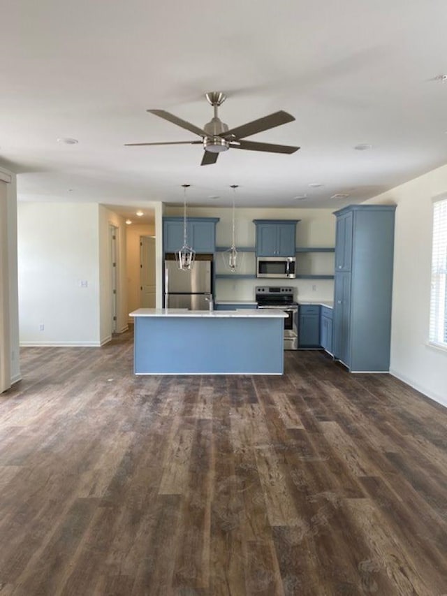 kitchen with hanging light fixtures, a kitchen island, stainless steel appliances, dark hardwood / wood-style flooring, and blue cabinetry