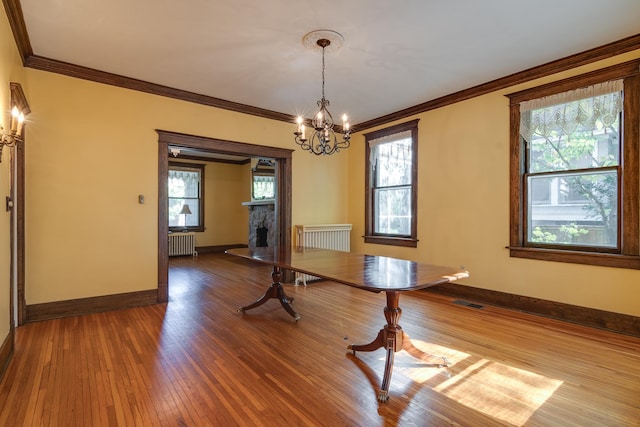 unfurnished dining area with ornamental molding, radiator, a chandelier, and hardwood / wood-style flooring