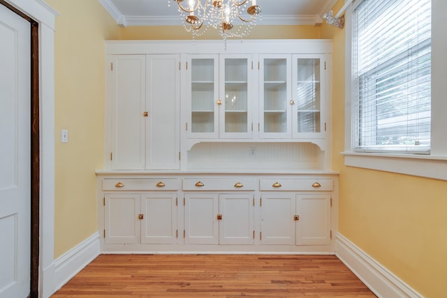 bar featuring light wood-type flooring, ornamental molding, and white cabinetry