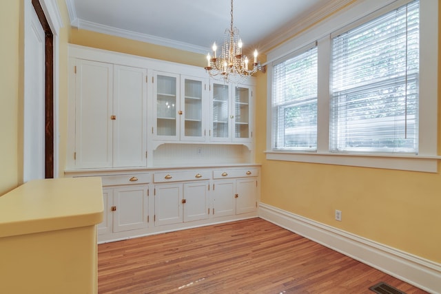 unfurnished dining area featuring crown molding, light hardwood / wood-style floors, and a chandelier