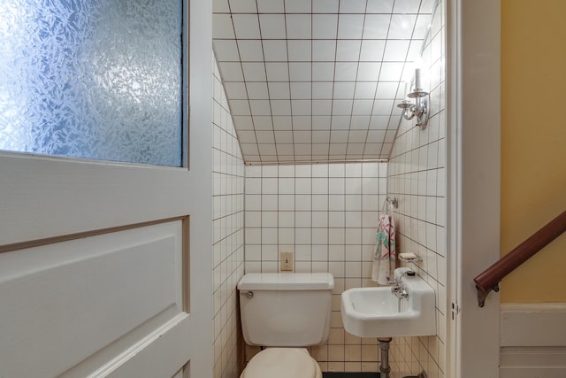 bathroom featuring tile walls and toilet