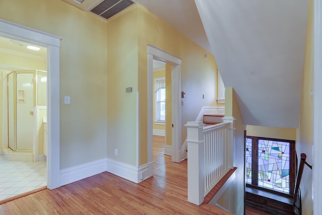 hallway featuring light wood-type flooring, crown molding, and vaulted ceiling