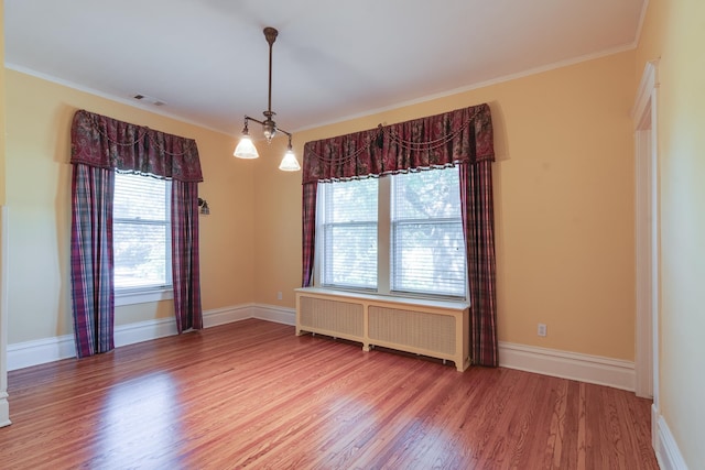 unfurnished room featuring crown molding, hardwood / wood-style floors, and radiator heating unit