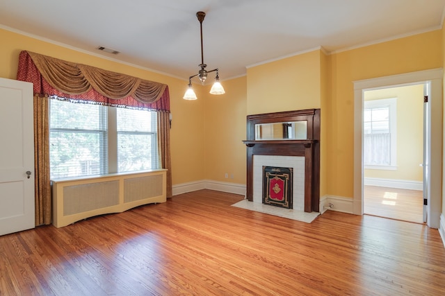 unfurnished living room with crown molding, a fireplace, radiator, and hardwood / wood-style floors