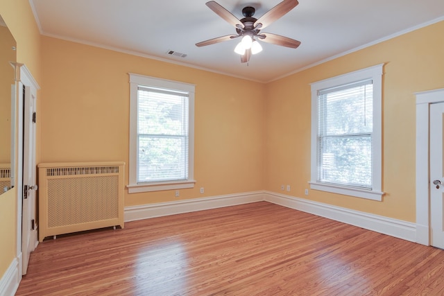 empty room featuring radiator, light hardwood / wood-style floors, a wealth of natural light, and crown molding