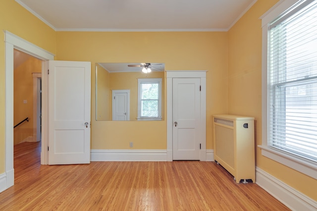 interior space featuring light hardwood / wood-style flooring, ceiling fan, ornamental molding, and radiator heating unit