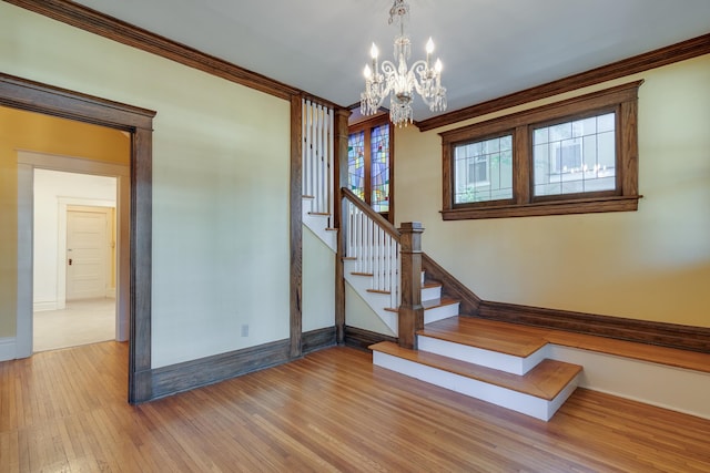 stairs with a chandelier, hardwood / wood-style floors, and crown molding