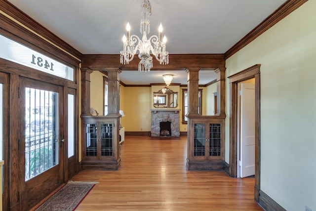 foyer entrance featuring a fireplace, ornamental molding, hardwood / wood-style floors, and a notable chandelier