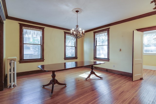 dining space featuring an inviting chandelier, hardwood / wood-style flooring, and crown molding