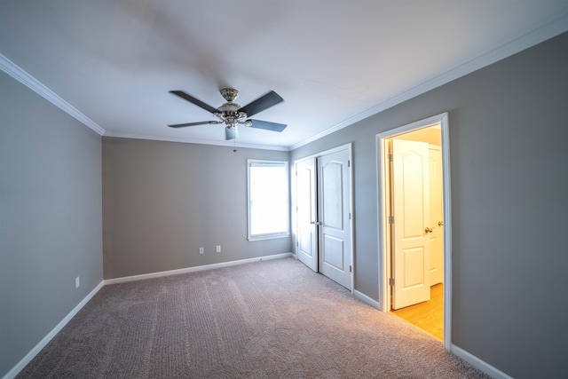 unfurnished bedroom featuring ceiling fan, light colored carpet, a closet, and crown molding