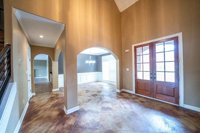 entryway featuring ornamental molding, an inviting chandelier, a towering ceiling, and french doors