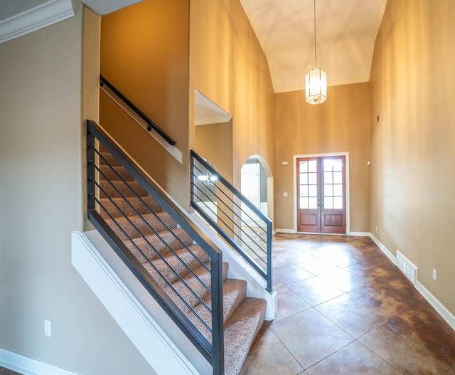 entryway with french doors, a notable chandelier, crown molding, and a high ceiling