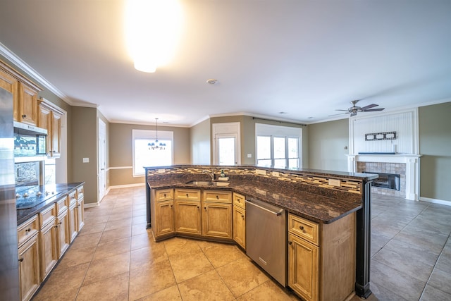 kitchen featuring a fireplace, dishwasher, decorative light fixtures, ornamental molding, and sink