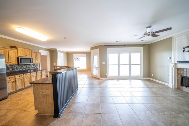 kitchen with decorative light fixtures, stainless steel appliances, ornamental molding, and tasteful backsplash