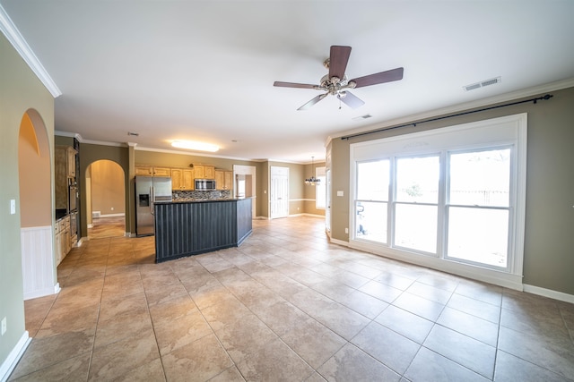 kitchen with light brown cabinets, appliances with stainless steel finishes, a center island, ceiling fan with notable chandelier, and crown molding