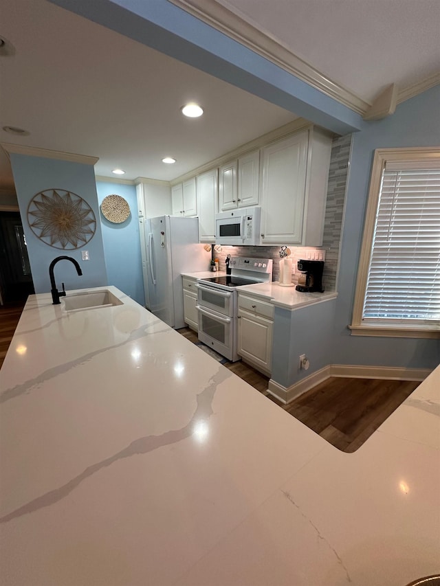 kitchen with sink, white appliances, white cabinetry, dark hardwood / wood-style floors, and crown molding