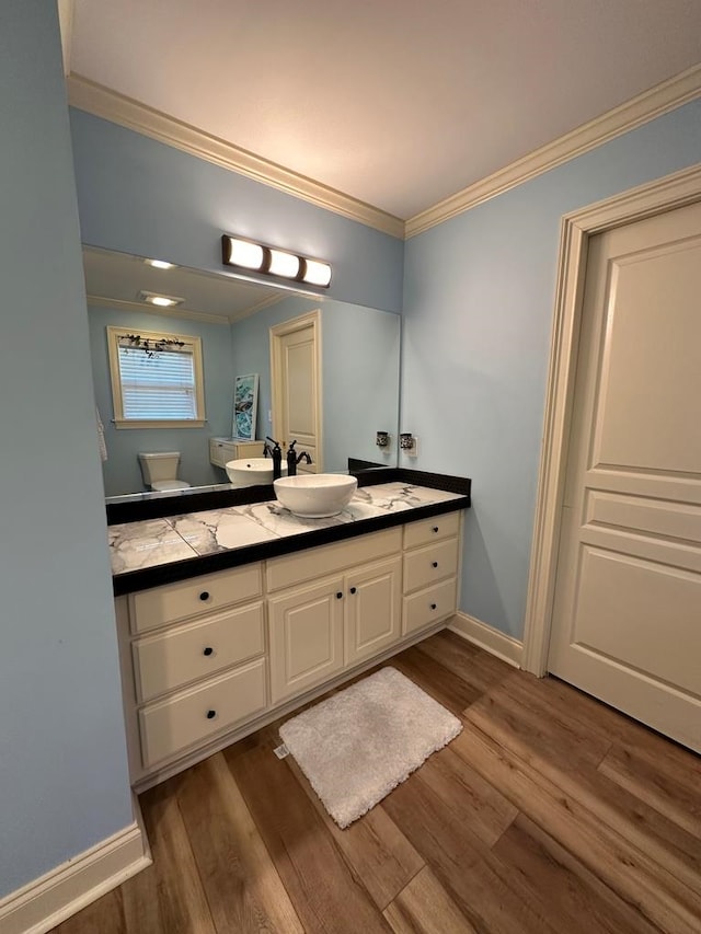 bathroom featuring wood-type flooring, ornamental molding, vanity, and toilet