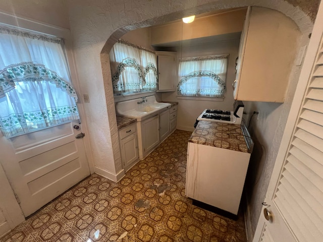 kitchen with white range, sink, and a healthy amount of sunlight