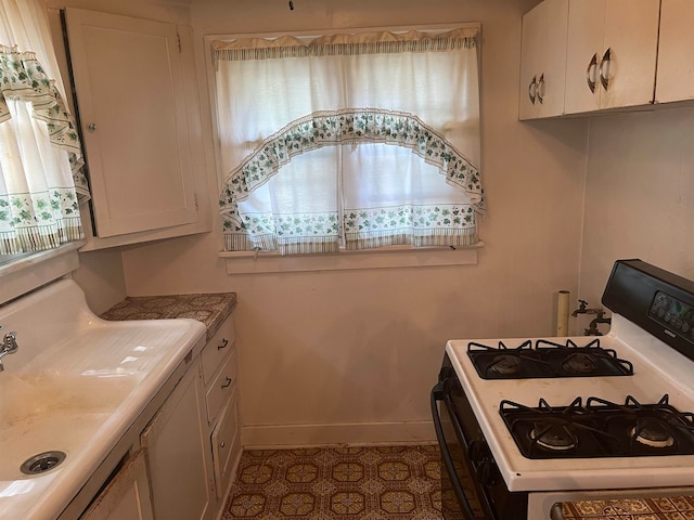 kitchen featuring white cabinets, white gas range oven, and light tile patterned floors