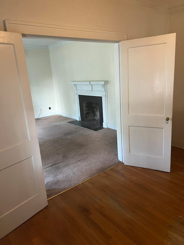 unfurnished living room with hardwood / wood-style flooring and crown molding