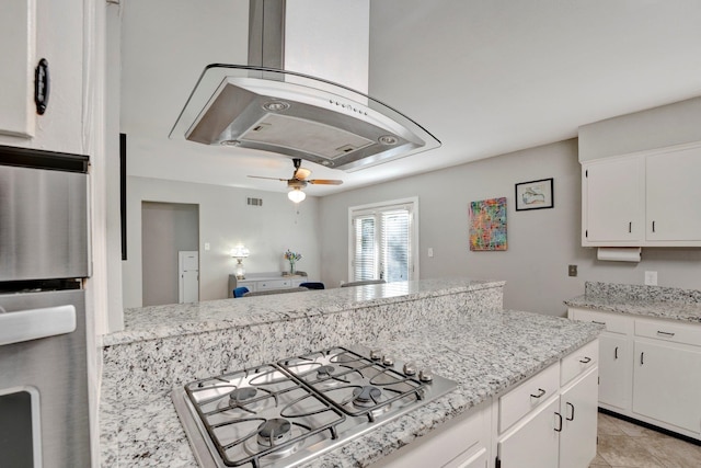 kitchen featuring appliances with stainless steel finishes, light tile patterned flooring, white cabinetry, light stone counters, and ceiling fan