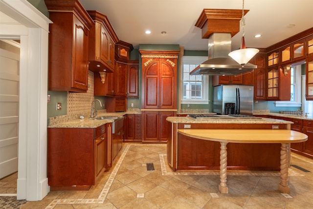 kitchen with hanging light fixtures, appliances with stainless steel finishes, island range hood, and a center island