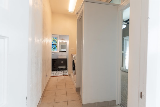 corridor featuring sink, light tile patterned floors, and washer and dryer