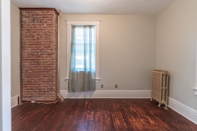 empty room with dark wood-type flooring and radiator