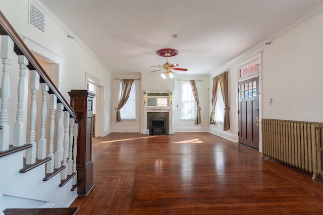 unfurnished living room with ceiling fan, radiator, crown molding, and dark hardwood / wood-style floors