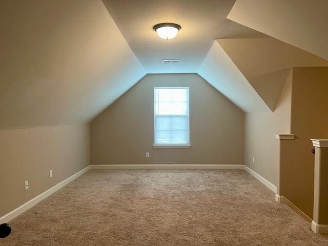 additional living space featuring light colored carpet and vaulted ceiling