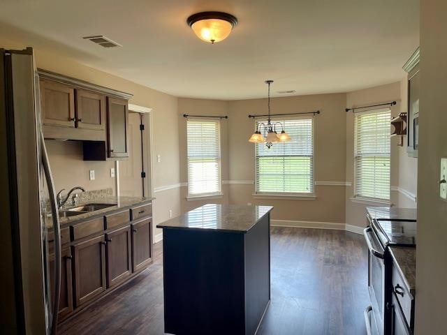 kitchen featuring pendant lighting, stainless steel appliances, a center island, dark hardwood / wood-style floors, and sink