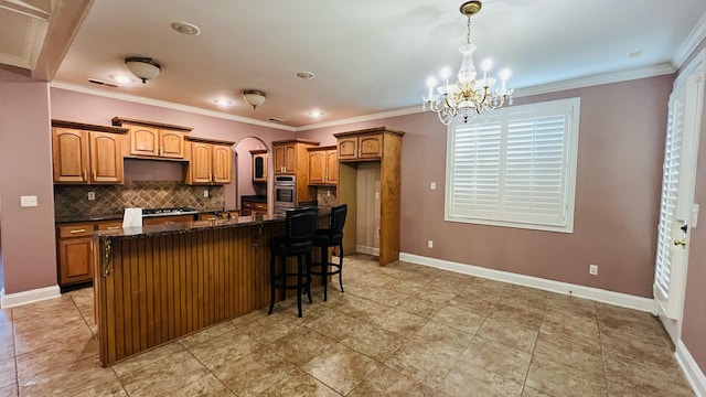 kitchen with backsplash, stainless steel oven, ornamental molding, and a kitchen island with sink