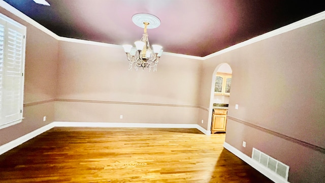 unfurnished dining area featuring hardwood / wood-style floors, a notable chandelier, and ornamental molding