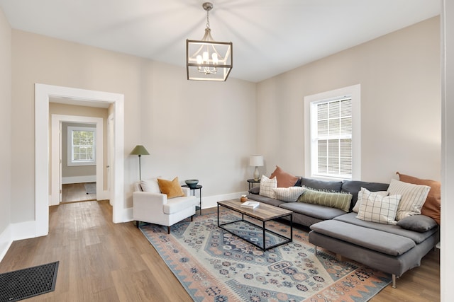 living room with light hardwood / wood-style floors, a chandelier, and plenty of natural light