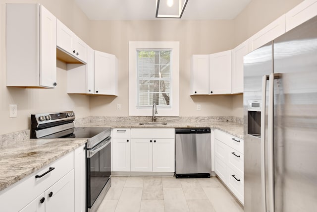 kitchen with light stone counters, appliances with stainless steel finishes, sink, and white cabinetry