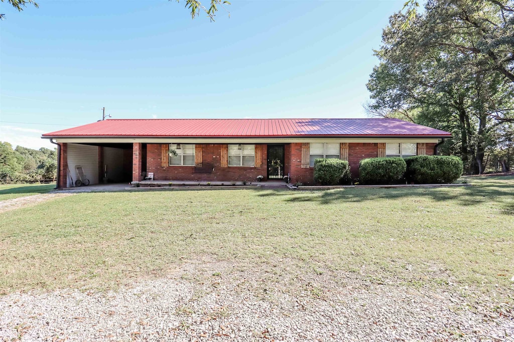 ranch-style home featuring a front lawn and a carport