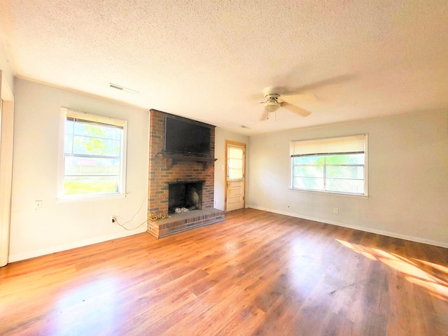 unfurnished living room featuring a fireplace, plenty of natural light, hardwood / wood-style floors, and a textured ceiling