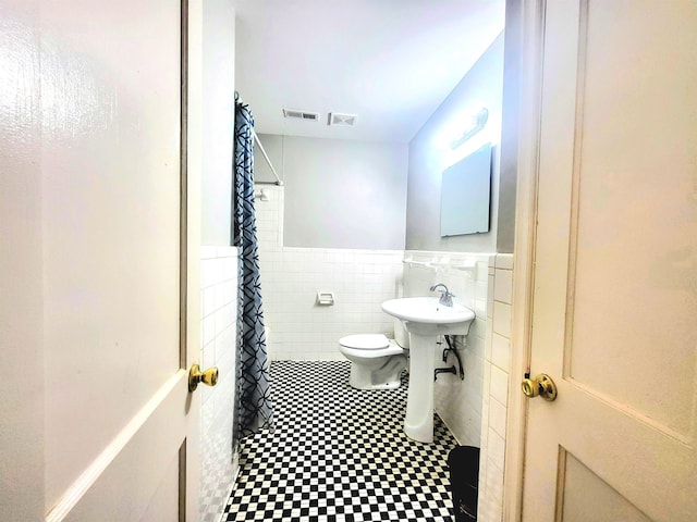 bathroom with tile walls, toilet, and a shower with shower curtain