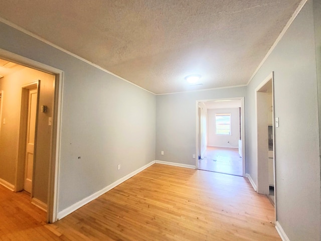 unfurnished room featuring crown molding, light hardwood / wood-style flooring, and a textured ceiling