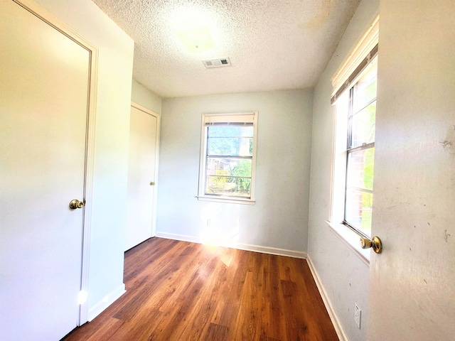 unfurnished bedroom featuring a textured ceiling, a closet, and dark hardwood / wood-style flooring