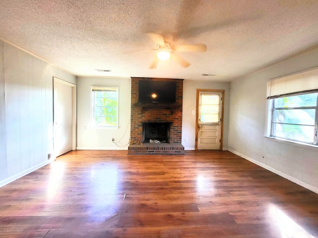 unfurnished living room with a textured ceiling, a fireplace, ceiling fan, and dark hardwood / wood-style flooring