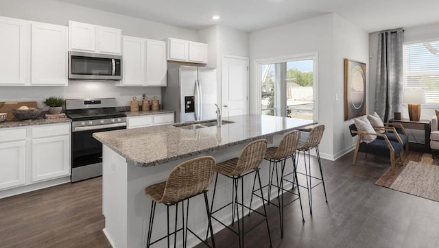 kitchen with a center island with sink, stainless steel appliances, dark hardwood / wood-style floors, and a wealth of natural light