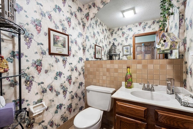 bathroom with tile walls, a textured ceiling, vanity, and toilet