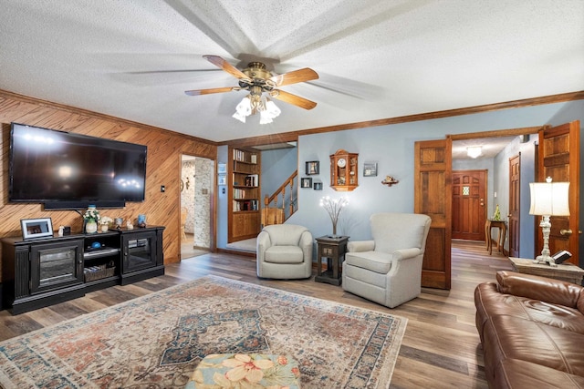 living room featuring ornamental molding, ceiling fan, a textured ceiling, and hardwood / wood-style floors