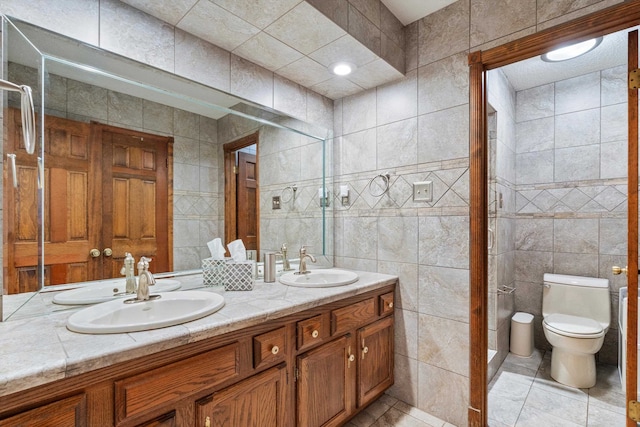 bathroom featuring vanity, tile walls, toilet, and a shower with door