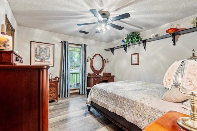 bedroom with light wood-type flooring, ceiling fan, and a textured ceiling